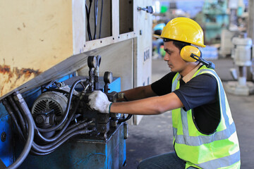 Fototapeta premium Technician engineer or worker in protective uniform standing and using computer while controlling operation or checking industry machine process with hardhat at heavy industry manufacturing factory