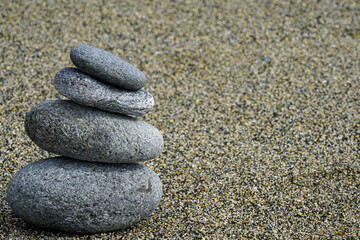 Fototapeta na wymiar Rocks stacked on a beach. Stacked stones in the sand with room for copy. Stacked rocks representing balance, a solid foundation and achieving goals.
