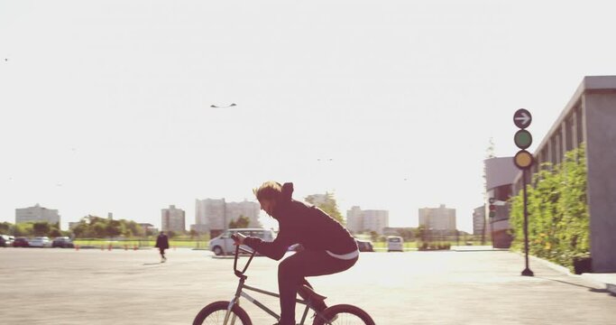 Go big or go home. Young confident biker adrenaline junkie BMX bicycle rider doing tricks outside in an urban setting. Sporty young man, daredevil, practicing some moves on his bicycle outside
