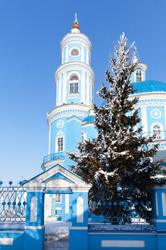 Famous Telma old temple in honor of Kazan Icon of Mother of God in classicism style 1816 during Christmas holidays. Decorated snowy Christmas tree near the entrance to church on cold winter day