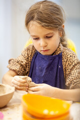 Cute little kid playing with modeling clay in pottery workshop, craft and clay art, child creative activities, education in Arts