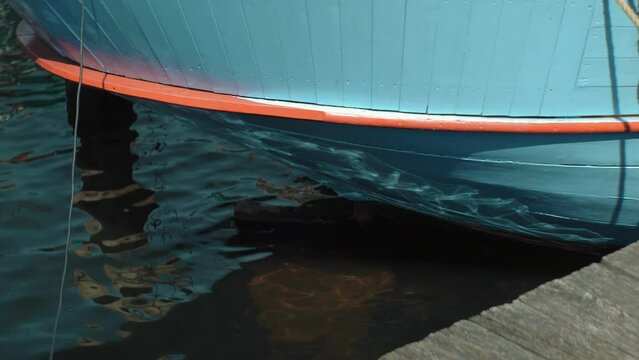 Water Reflecting The Sun On The Back Of A Wooden Historical Old Dutch Sailing Boat Laying In The Habor. Close Up 4K Slow Motion