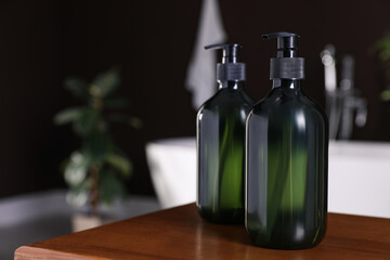 Dispensers of liquid soap on wooden table in bathroom, space for text
