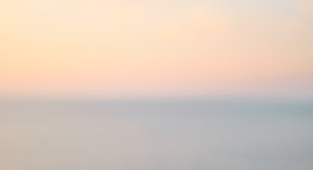 Colorful sunset with long exposure effect, motion blurred. Defocused sunrise sky and ocean nature background with blurred panning motion