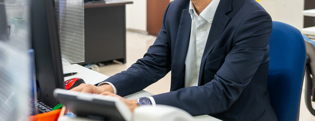 オフィスワーク　パソコンのモニターを見ながら作業するビジネスマン