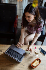 Pretty young asian business woman using laptop in modern cafe. 