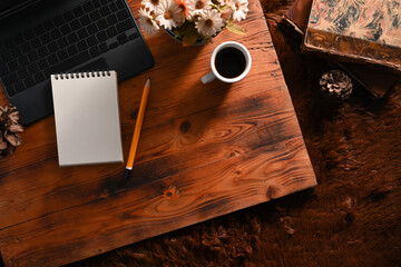 Empty notebook, laptop computer, coffee cup and vintage book on wooden table.