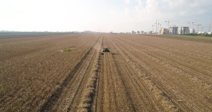 Kibbutz, Israel - 25 November 2021: Aerial view of a tractor shredding a cotton field leftover, Kibbutz Saar, Mate Asher, Israel
