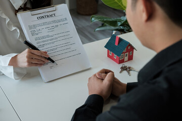 Real estate brokers point to a contract paper and advise customers to sign their names. customer...