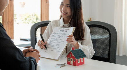 Real estate brokers point to a contract paper and advise customers to sign their names. customer...