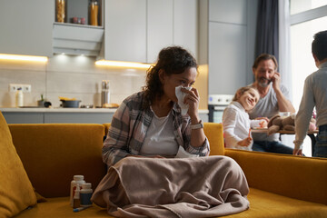 Sick lady at home blowing nose into tissue