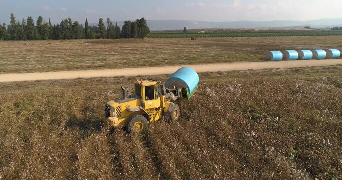 Kibbutz, Israel - 25 November 2021: Aerial view of a tractor loading cotton bales on truck, Kibbutz Saar, Mate Asher, Israel.