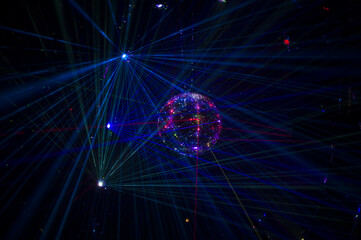 Mirrored Disco Ball and bright beams at the night party. Party attribute reflects Lazer lights. Abstract background with defocused rays. Night club atmosphere. Installation at Vilnius light festival