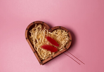 Wooden gift box in the shape of a heart and two red dried flowers