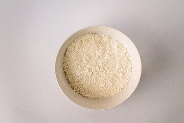 flour in a white ceramic plate on a white background with copy space
