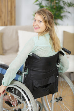 young disabled woman in wheelchair at home in living room