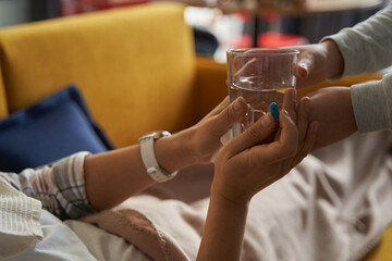 Glass of water and pill passed to hands of person
