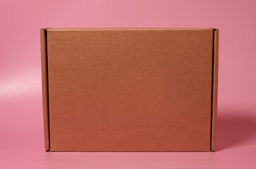 Closed cardboard box on a solid pink background