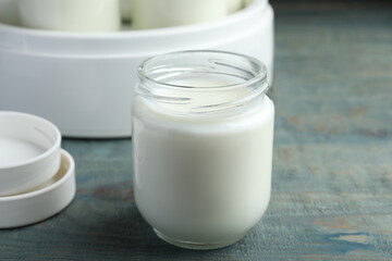 Obraz na płótnie Canvas Glass jar with tasty yogurt on blue wooden table