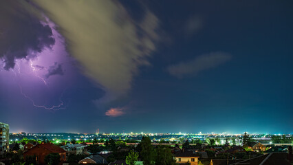 Thunderstorm over the city at night, bright lightning among dense clouds