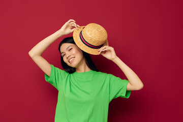 Portrait Asian beautiful young woman gestures with his hands with a hat in a green t-shirt red background unaltered