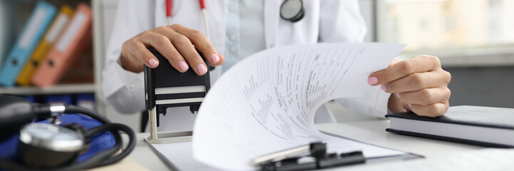 Doctor puts a stamp on medical documents closeup