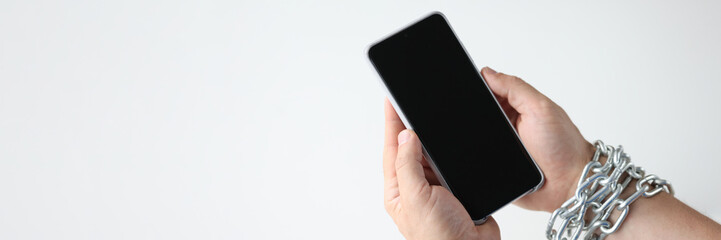 Hands wrapped in chain hold black smartphone closeup