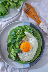 Delicious spinach crepes green colored pancake with vegetables on a table