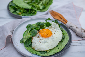 Delicious spinach crepes green colored pancake with vegetables on a table