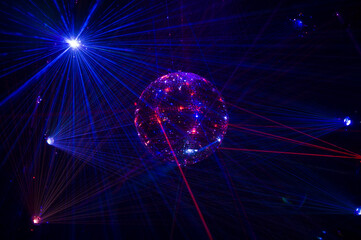 Mirrored Disco Ball and bright beams at the night party. Party attribute reflects Lazer lights. Abstract background with defocused rays. Night club atmosphere. Installation at Vilnius light festival