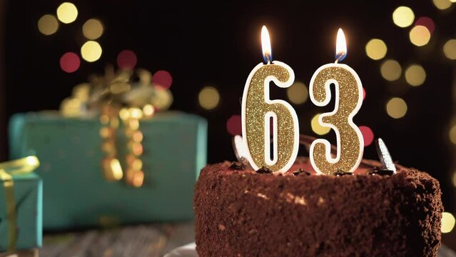 Birthday candle number sixty three on a sweet cake on the table, 63rd birthday. Fire from the lighter, blow out the holiday candle.