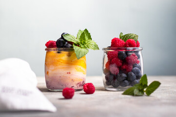 yogurt with mango and berry jam with blueberry, raspberry and mint leaves in the glass