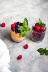 yogurt with mango and berry jam with blueberry, raspberry and mint leaves in the glass