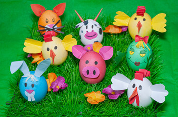 Bright Easter eggs with animal stickers on a green grass moss stand. Animals on Easter Ears