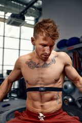 Obraz premium Portrait of sportsman checking heart rate on fitness trekker after training in gym