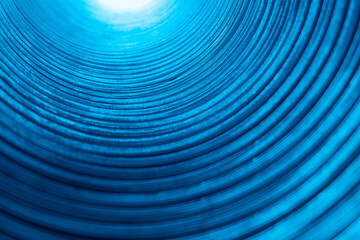 Fluorescent background. Blur glowing curves. Ripple texture. Futuristic tunnel illumination. Defocused neon blue color light on ridged abstract overlay.
