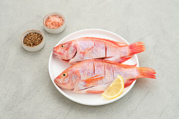 Ikan Nila Merah (Raw red tilapia fish) is a kind of freshwater fish consumption, served on white...