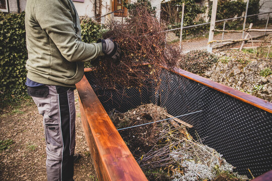 Man filling green waste and plant cuttings into raised bed