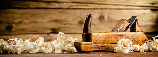 A planer with wooden shavings on the table. On a wooden background. High quality photo