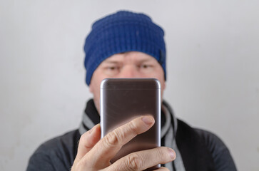 A man holds a gray phone in front of his face.