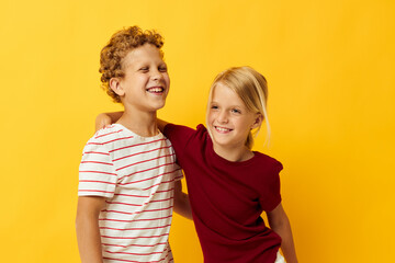 Cute stylish kids standing side by side posing childhood emotions yellow background