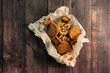 Homemade cookies with chocolate and nuts on a wooden table with a background blur.