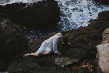 woman lying on her back on a rocky seashore nature
