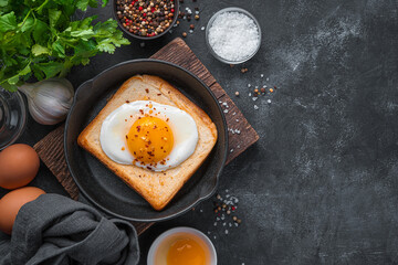 Fried eggs on fried toast on a black background. Top view, copy space.