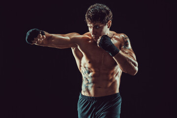Portrait of aggressive boxer who training and practicing jab on black background. Sport concept - obrazy, fototapety, plakaty