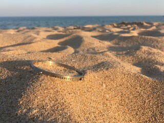 Wanderlust, close up of bracelet on sand beach. Sardinia. Italy