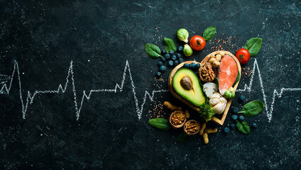 Food banner. Healthy foods low in carbohydrates. Food for heart health: salmon, avocados, blueberries, broccoli, nuts and mushrooms. On a black stone background. Top view.