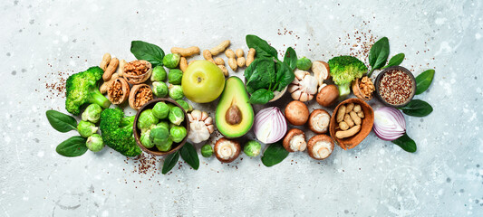 Food for heart health. Green vegetables, fruits, nuts and mushrooms. On a gray stone background....