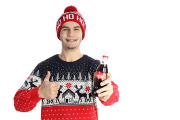 Odessa, Ukraine - 20 december 2021: Guy in Christmas sweater holds Coca-cola bottle, isolated on...