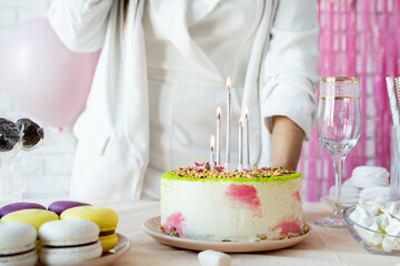 Woman in white party clothes preparing birthday table, lighting the candles